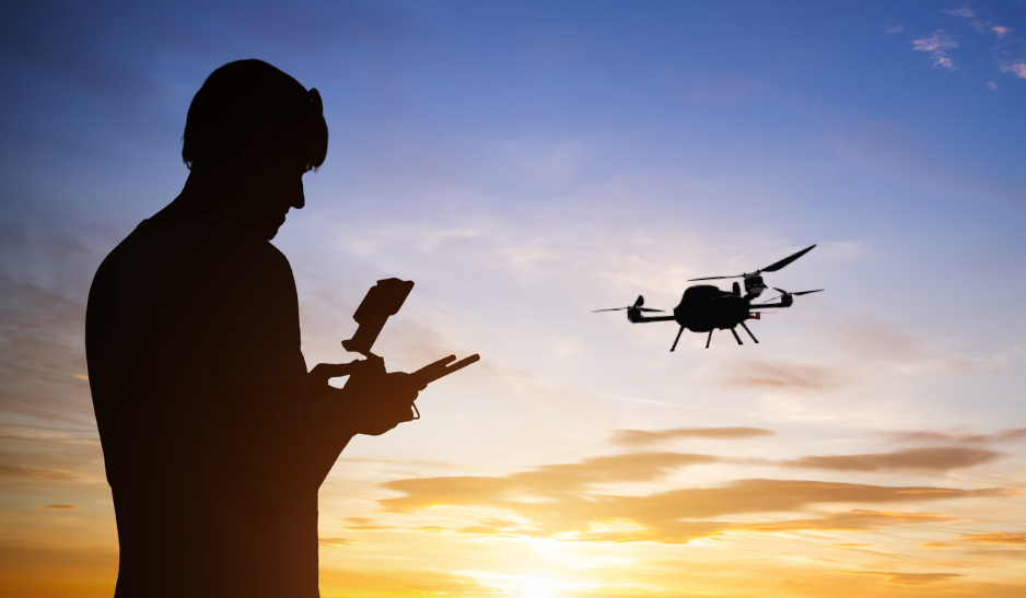 Man controlling a drone for land surveying at sunset